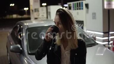 休息一下。 美丽微笑的女人靠在车上，拿着黑色纸杯，喝着咖啡。 正面观点